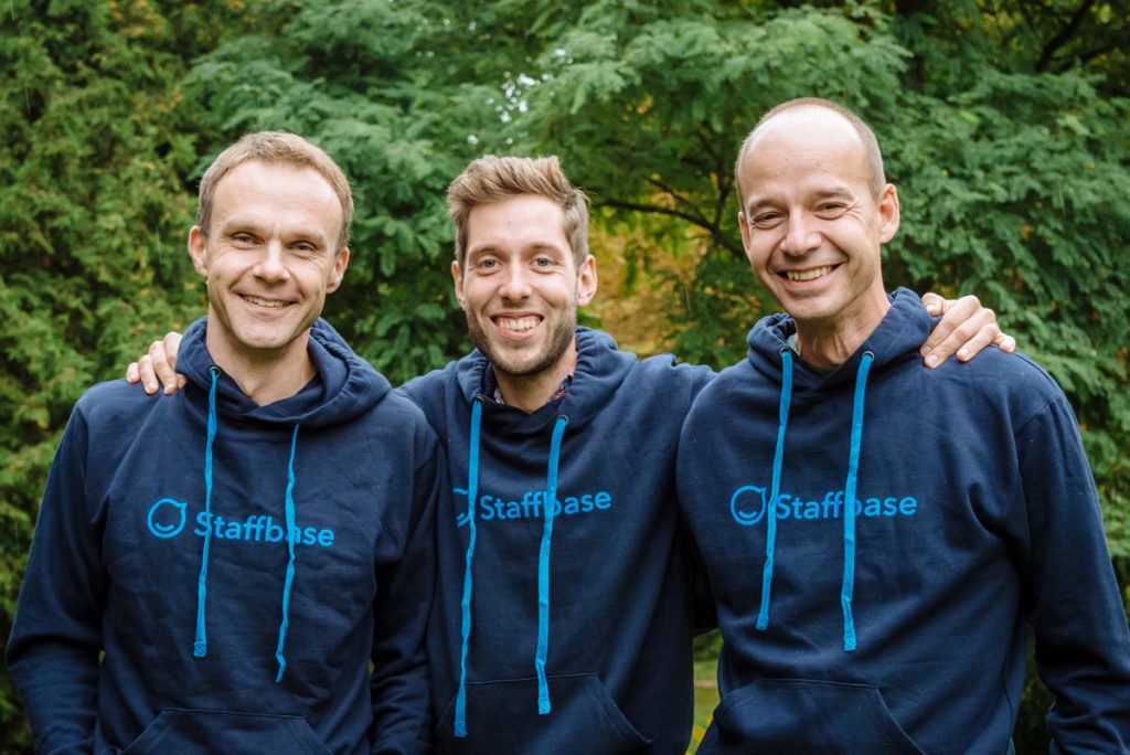 A landscape photo of three Staffbase cofounders in blue branded hoodies: Frank Wolf (president), Martin Böhringer (CEO) and Lutz Gerlach (COO)