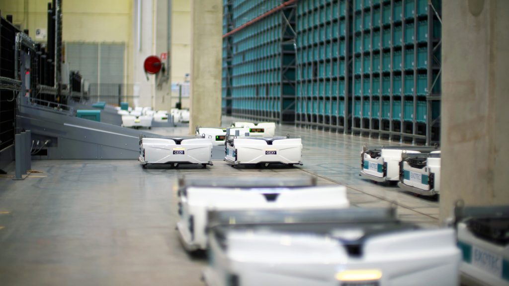 An image of Exotec Skypod robots, which are short and white with a wide square top, in a warehouse