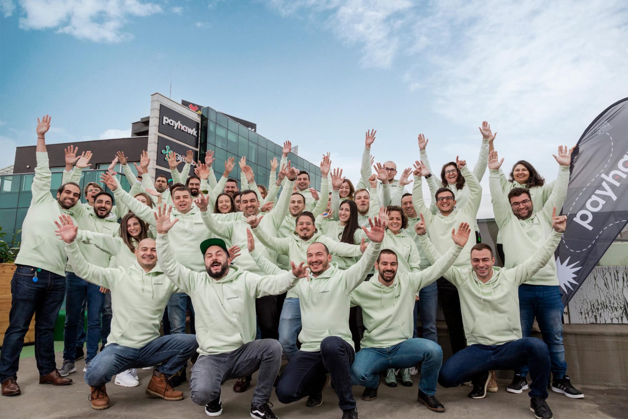 A landscape image of the Payhawk team, all wearing light green trademark hoodies.