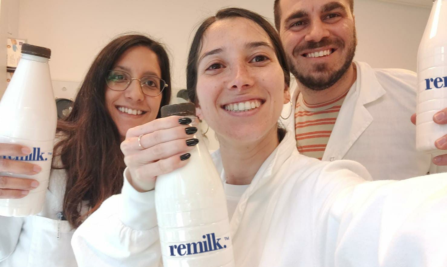 An image of Remilk workers holding bottles of their animal-free milk