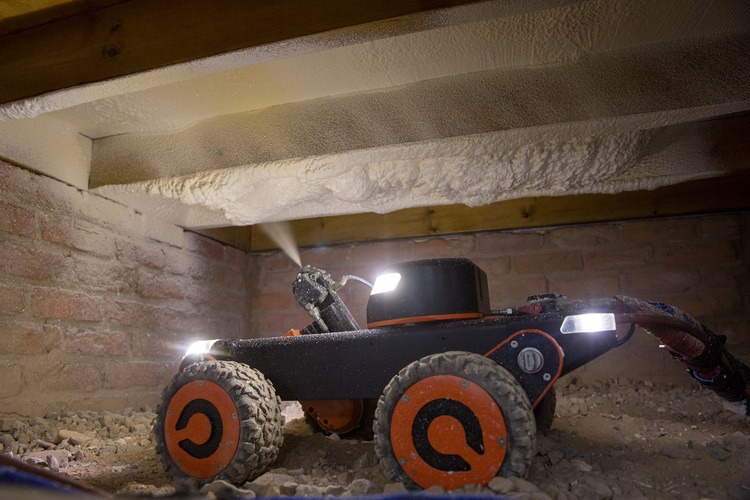 An image of the Q-Bot spraying foam-like insulation below the floorboards of a house