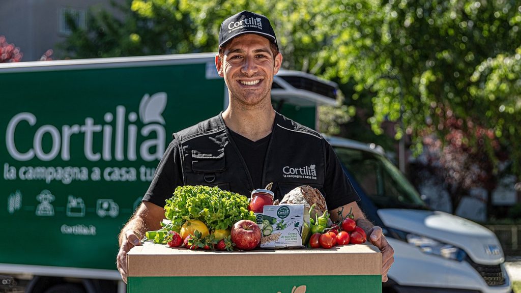 An image of a Cortilla delivery driver carrying a box full of fruit