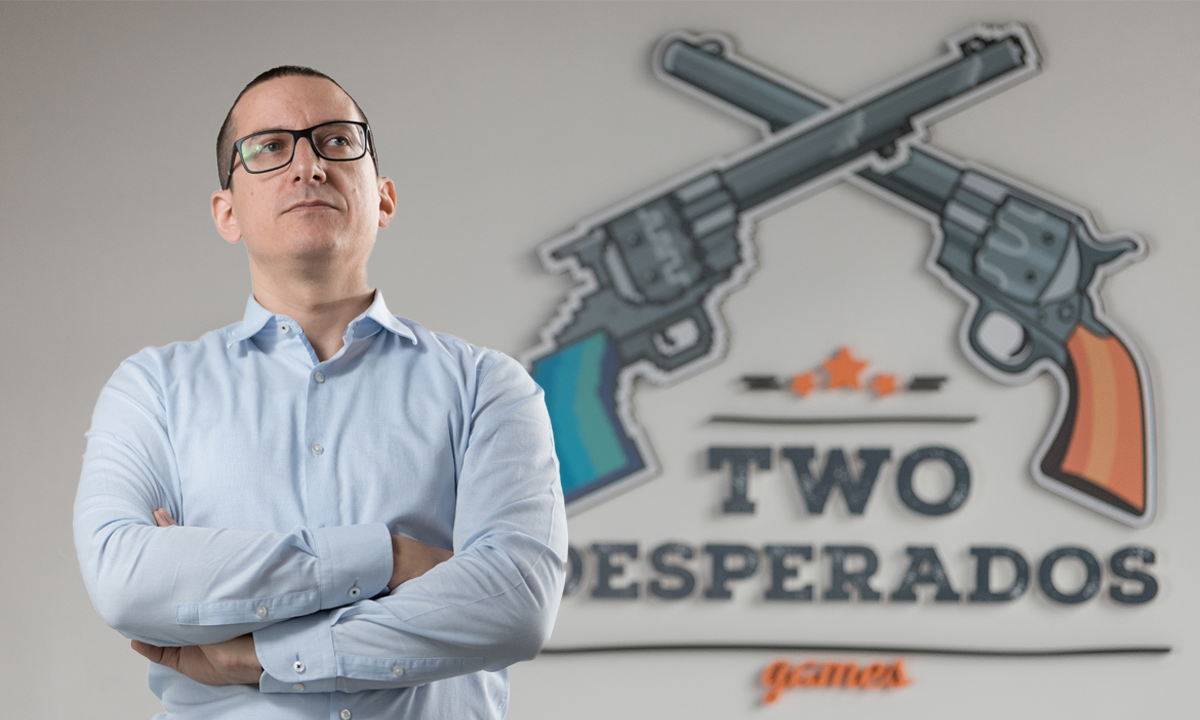 The founder of Two Desperados in front of the logo on the wall